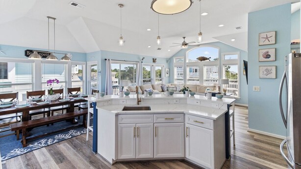 A spacious kitchen with a large island, white cabinetry, and a ceiling fan. - Sun Realty gorgeous pet-friendly oceanside home w/ pool, hot tub, & elevator! (Corolla)