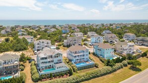 A coastal residential area with houses, a swimming pool, and a clear view of the ocean. - Sun Realty gorgeous pet-friendly oceanside home w/ pool, hot tub, & elevator! (Corolla)