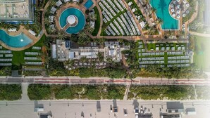 An aerial view of a resort with multiple swimming pools, a beach area, and a promenade.