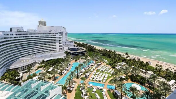 A resort with a large pool area, beach access, and a view of the ocean.