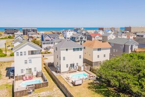 Een woongebied met huizen, een zwembad en een strand op de achtergrond.