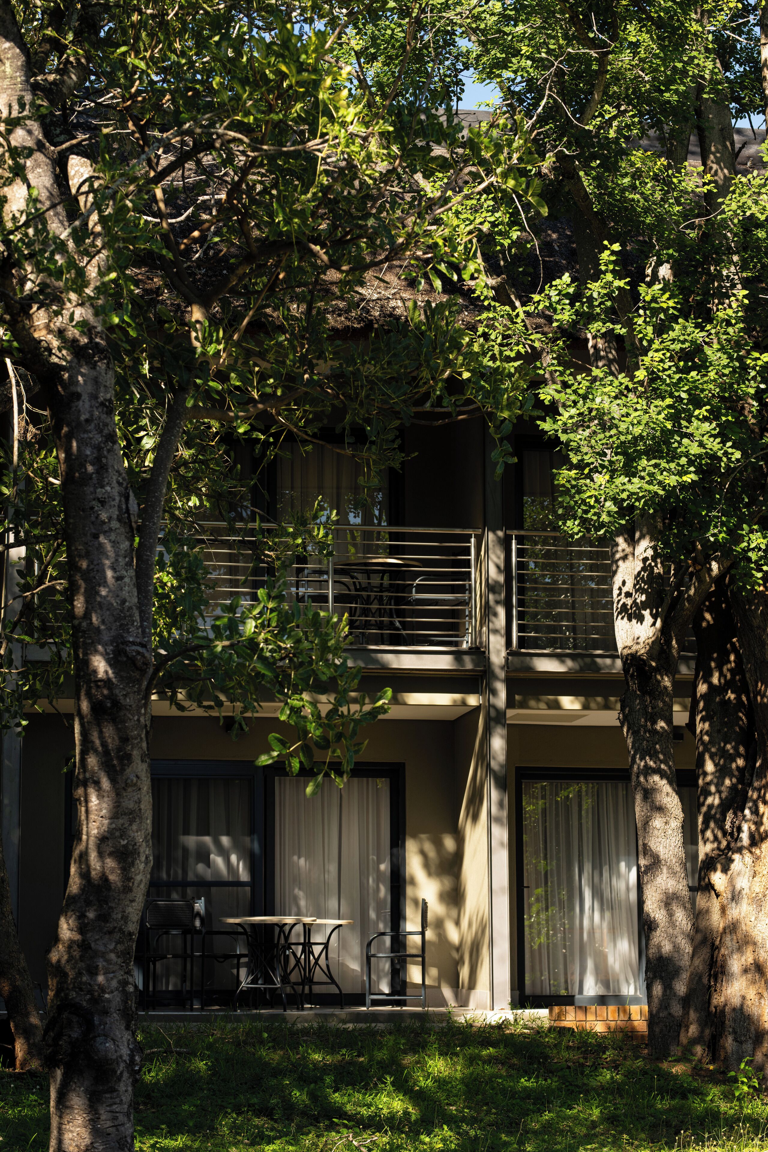 A two-story building with a balcony, outdoor seating, and a grassy area.