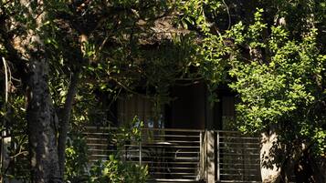 A two-story building with a balcony, outdoor seating, and a grassy area.
