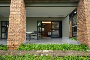 A covered outdoor area with brick pillars, a seating area, and a glass door leading inside.
