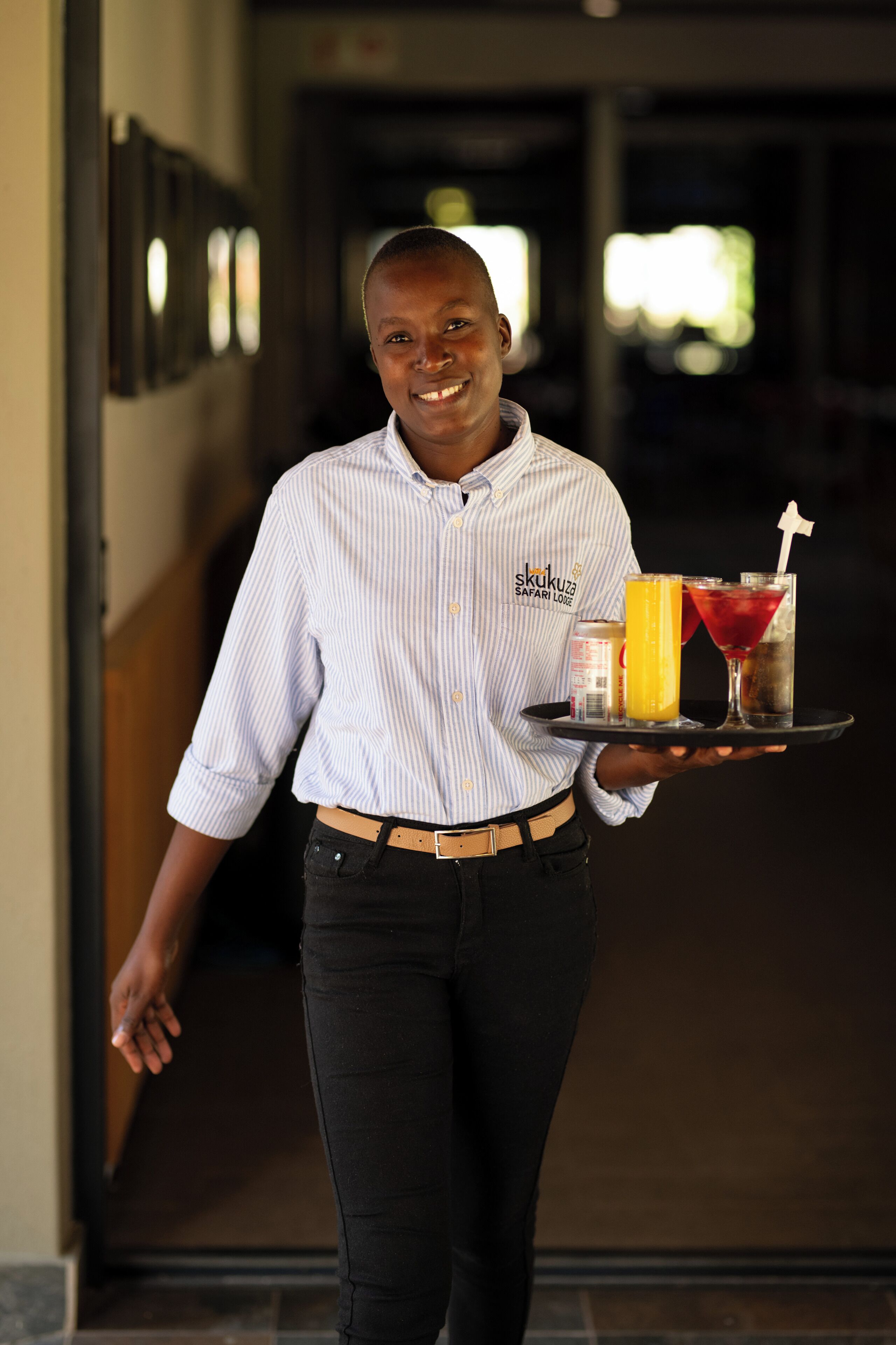 A person holding a tray with a drink and a sandwich.