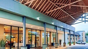 A modern building with a covered entrance, large glass windows, and outdoor seating areas.