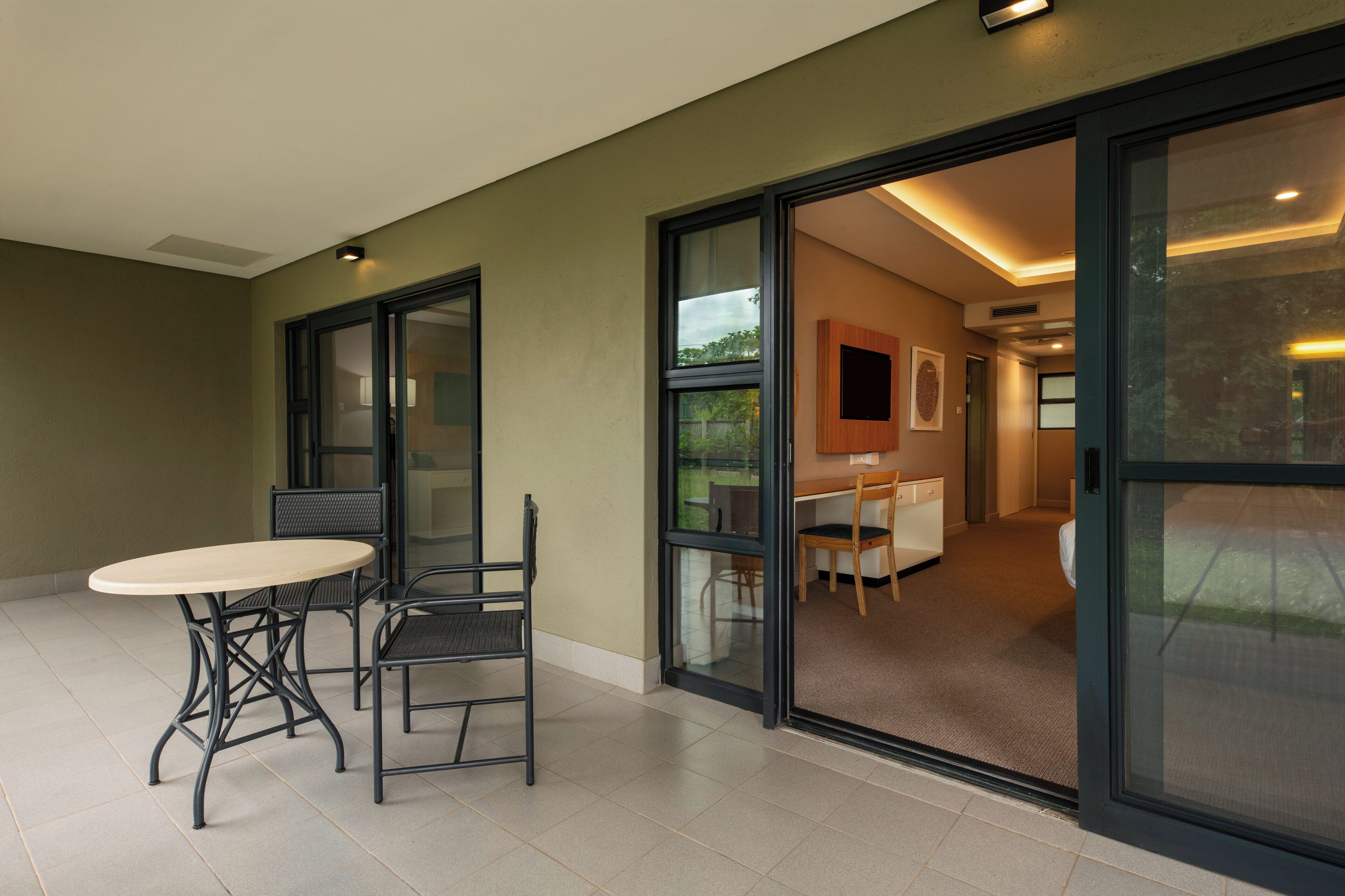 A modern room with a sliding glass door leading to a dining area, a small table with chairs, and a ceiling light.