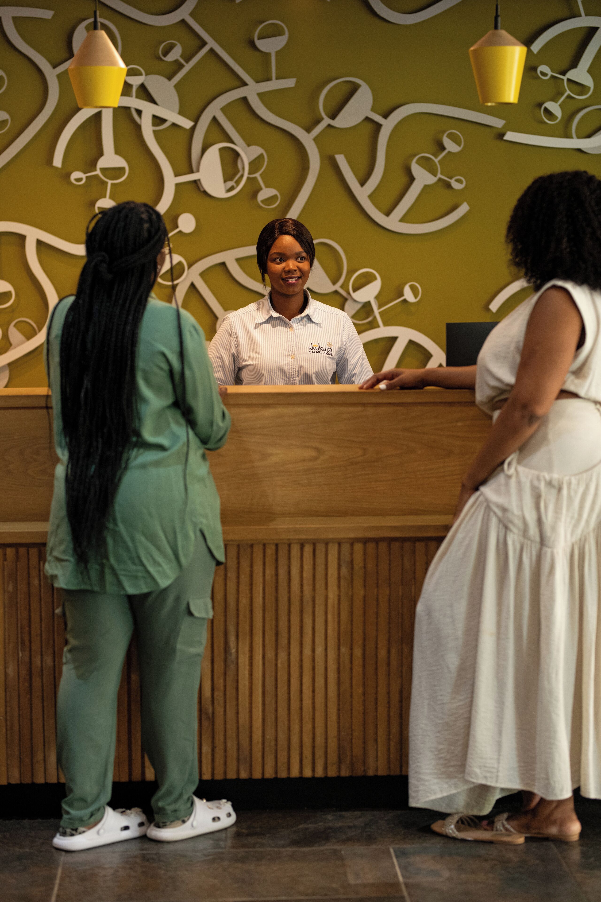 A reception desk with a wooden panel design and hanging pendant lights.