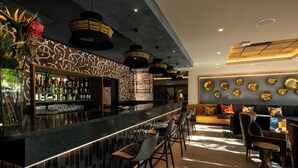 A bar area with a long counter, multiple stools, and a variety of bottles and glasses.