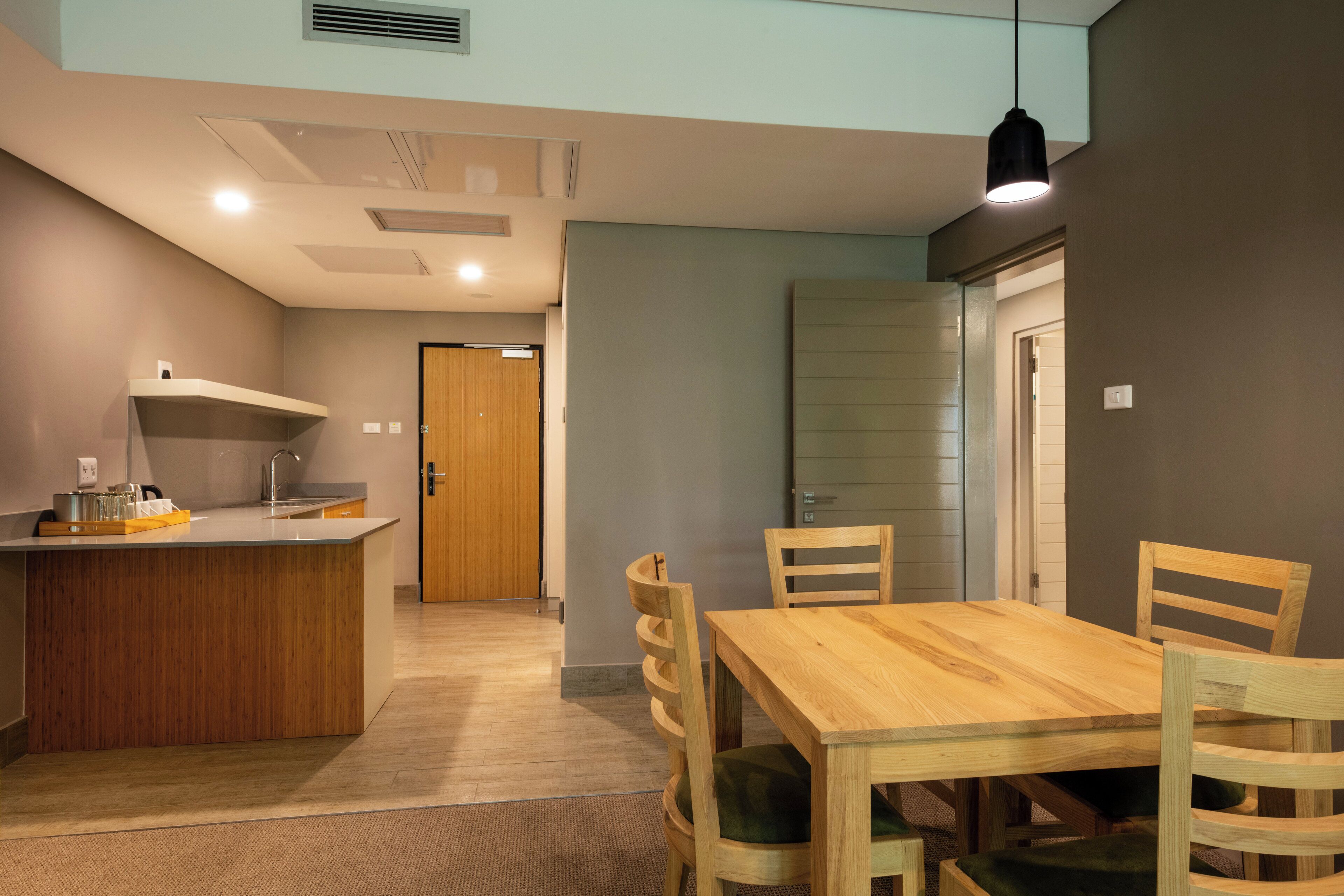 A modern kitchen with a wooden island, a dining table with chairs, and a pendant light.