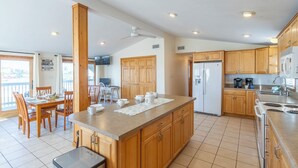 Una cocina amplia con armarios de madera, una isla central y un comedor con sillas y una mesa.