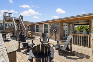 A wooden deck with Adirondack chairs and a table, a covered area with a railing, and a staircase leading to a deck. - Pet-friendly, updated oceanside home in Salvo! (Salvo)