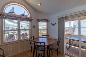 Enjoy meals around the large table with four chairs, surrounded by a high ceiling and large windows offering a view of the deck and surrounding buildings.