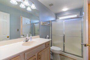 Bathroom features a large mirror, sink, and glass shower enclosure.