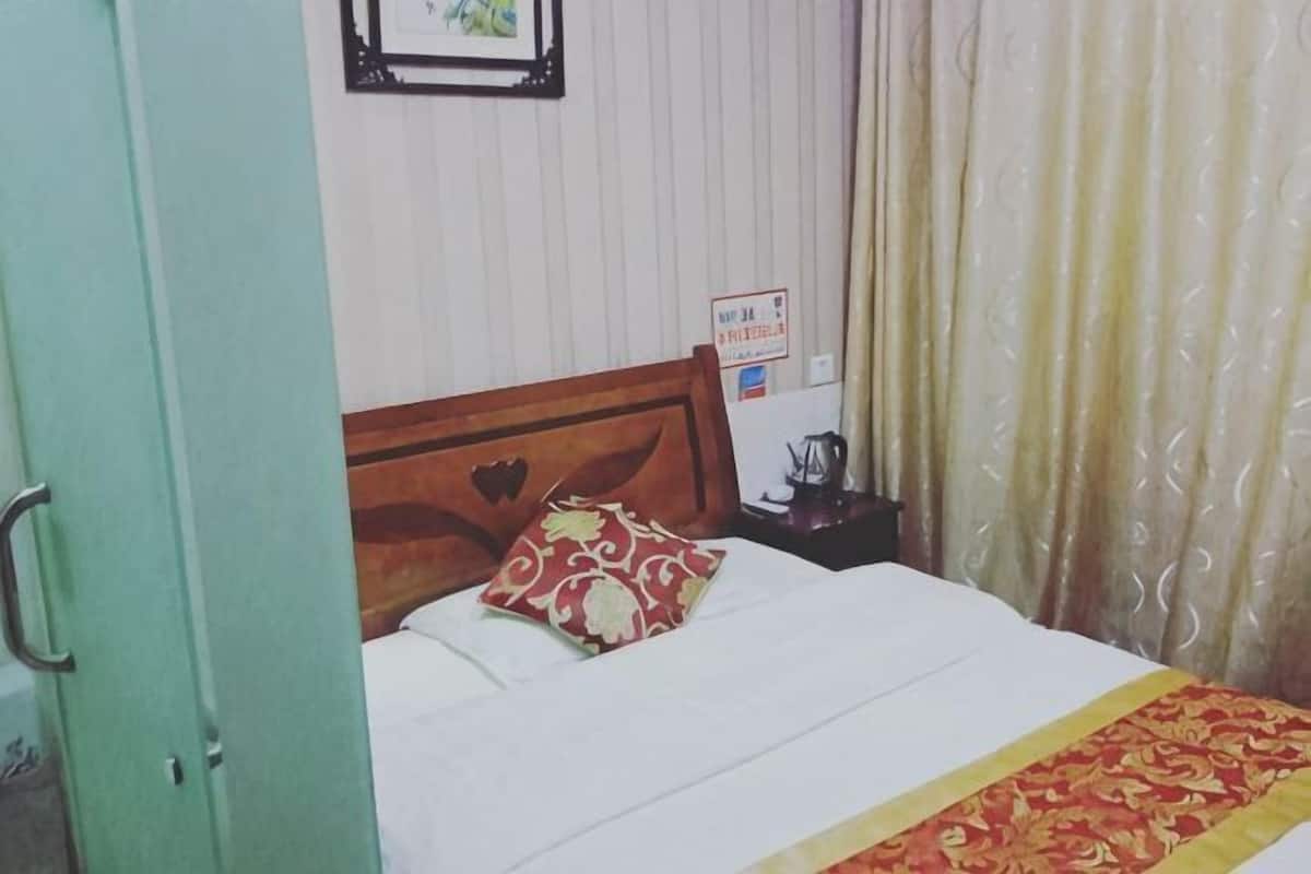 A bed with a wooden headboard, a red patterned pillow, and a white bedspread.