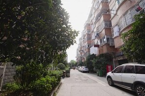A residential street with multi-story buildings, parked cars, and greenery along the sidewalk. - Hefei Ruyi Inn (Hefei)