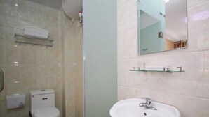 A bathroom with a toilet, sink, and glass shower enclosure.
