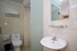 A bathroom with a toilet, sink, and glass shower enclosure.