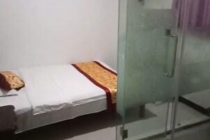 Una habitación pequeña con una cama, un separador de vidrio y una puerta.