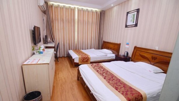 A hotel room with two beds, a desk, a chair, a TV, and a curtain.
