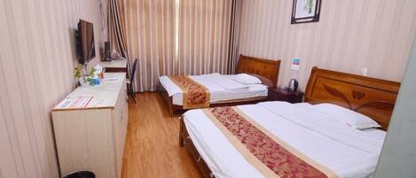 A hotel room with two beds, a desk, a chair, a TV, and a curtain.
