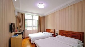 A hotel room with two single beds, a wooden desk with a chair, a television, and a window with curtains. - Hefei Ruyi Inn (Hefei)