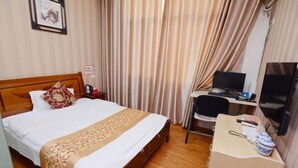 A hotel room with a wooden bed, a desk with a computer, and a television.