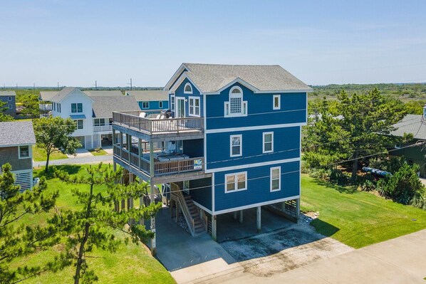 A two-story residential building with a balcony on the upper floor, a covered front porch, and a visible garage.