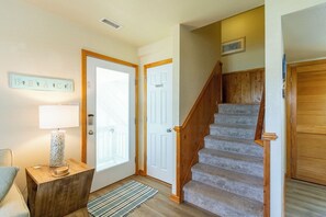 A staircase with wooden railings leading to a private door, a lamp on a side table, and a rug on the floor.