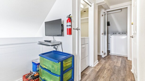 Een wasserette met een wasmachine, een droger en een brandblusser aan de muur.