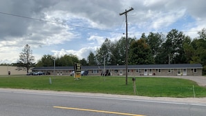 Un motel avec un panneau indicateur, un parking et un bâtiment doté d’un toit plat.