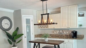 Een moderne keuken met witte kasten, een houten eettafel en een hanglamp.