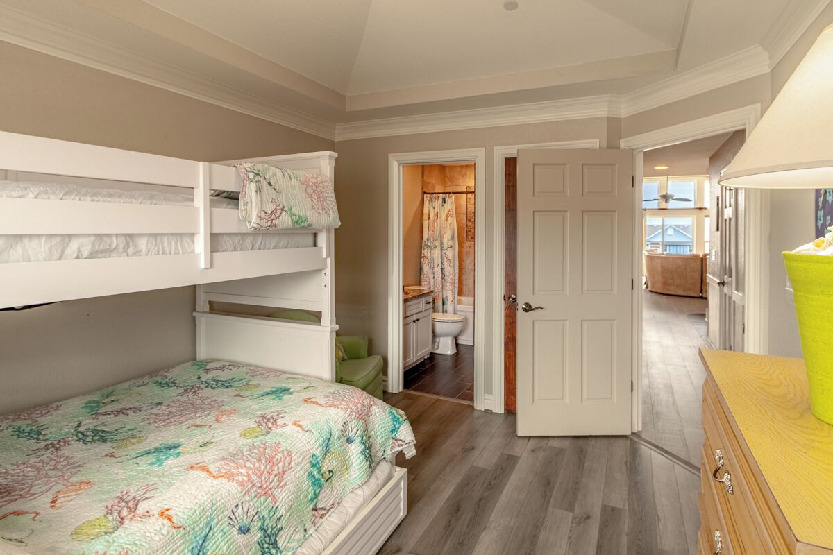 A bedroom with bunk beds, a bathroom with a toilet and shower, and a wooden dresser.