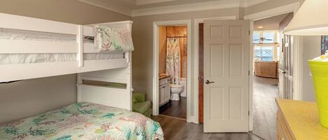 A bedroom with bunk beds, a bathroom with a toilet and shower, and a wooden dresser.
