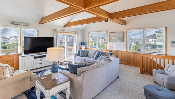 A spacious living room with a large flat-screen TV, multiple sofas, and a wooden ceiling structure. - Oceanside home in Hatteras 200 yards from beach, Hot Tub (Hatteras)