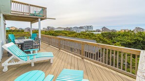 A wooden deck with outdoor furniture, a railing, and a view of houses in the background. - Oceanside home in Hatteras 200 yards from beach, Hot Tub (Hatteras)