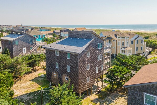 A coastal residential area with houses featuring a mix of modern and traditional architecture, some with visible balconies and others with flat roofs.