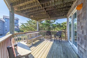 A wooden deck with a bench, a chair, and a table.