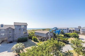 Una zona residencial costera con varias casas, algunas elevadas sobre pilotes, y una vista despejada del océano.