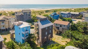 A coastal residential area with multiple two-story houses, some with balconies, and a beach in the background. - Semi Oceanfront home in Avon w/ ocean views (Avon)