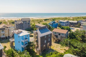 A coastal residential area with multiple two-story houses, some with balconies, and a beach in the background.