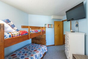 Une chambre avec un lit superposé, une commode et une porte sur laquelle est apposée une pancarte.