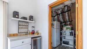 Cocina compacta con refrigerador, microondas y una pequeña encimera con licuadora.