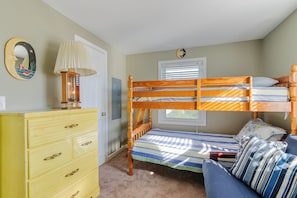 Un dormitorio con literas, cómoda, lámpara y ventana con persianas.