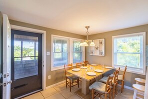 A dining area with a table set for four, wooden chairs, and a chandelier.