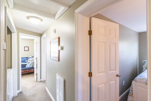 A hallway with a door, a radiator, and a bed in the background.