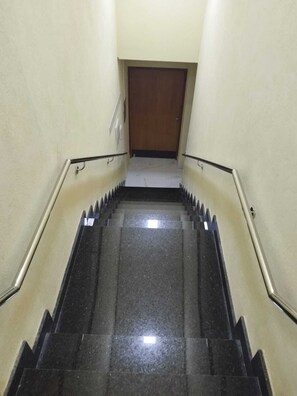 A staircase with black steps and metal handrails, leading to a wooden door at the top. - Hotel londres (Gama)