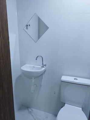 A small, modern bathroom with a white sink, mirror, and toilet. - Hotel londres (Gama)