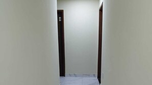 A narrow hallway with white marble flooring and plain walls. - Hotel londres (Gama)