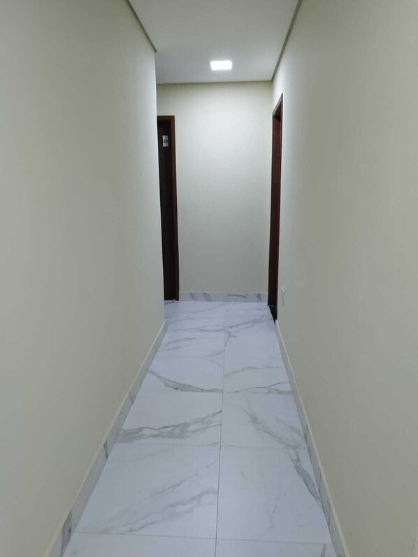 A narrow hallway with white marble flooring and plain walls. - Hotel londres (Gama)